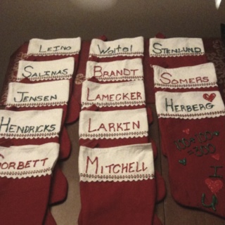 several red socks with embroidered names on them sitting on a table next to a lamp