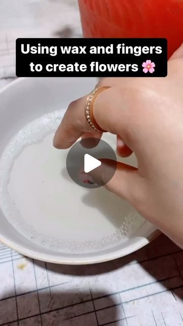 a person using wax and fingers to create flowers on a white plate with text overlay that reads, using wax and fingers to create flowers