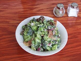 a white plate topped with broccoli and other food on top of a wooden table