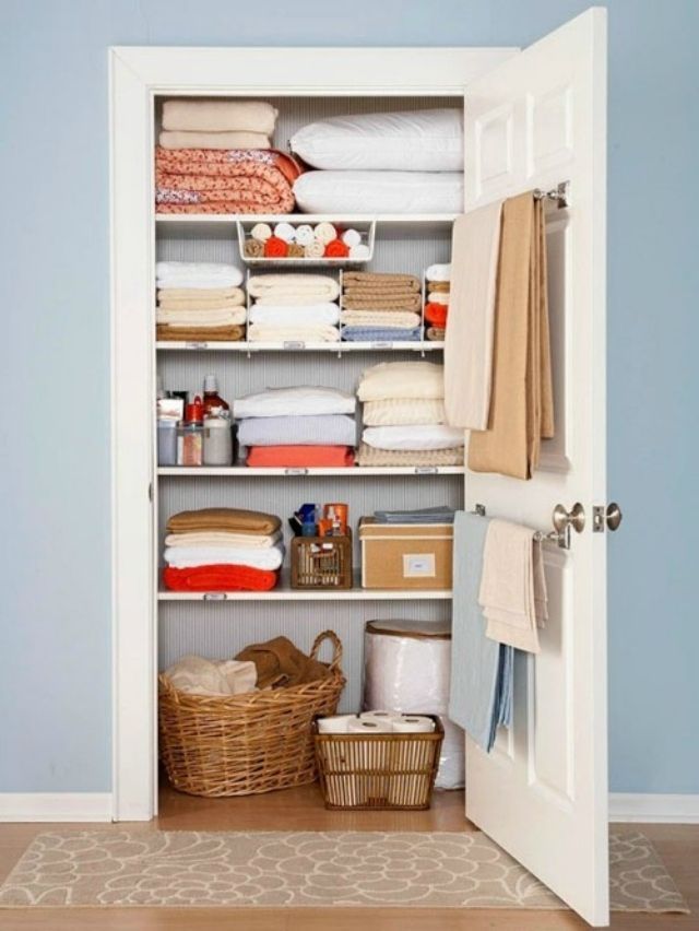 an open closet with towels, blankets and other items in baskets on the shelves next to it