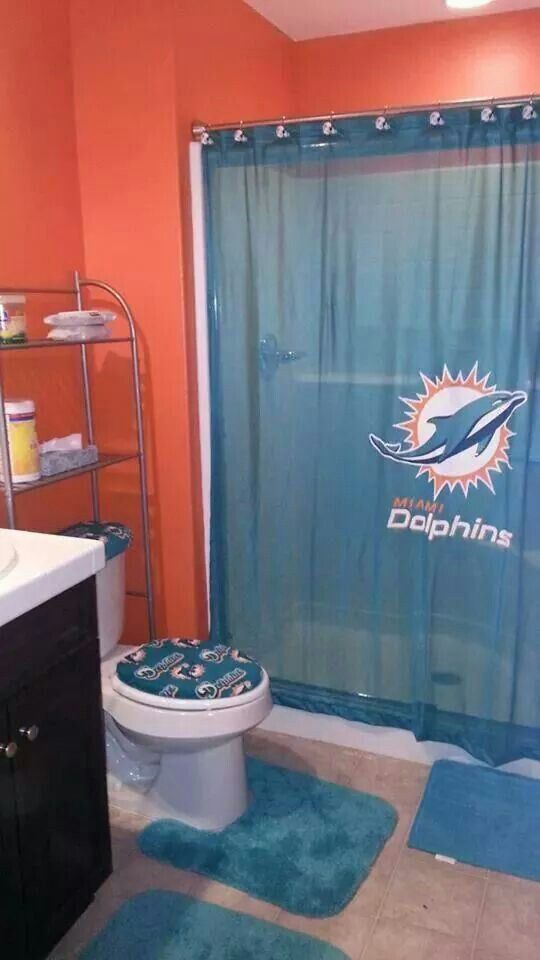 a bathroom with a miami dolphins shower curtain and rugs on the floor in front of it