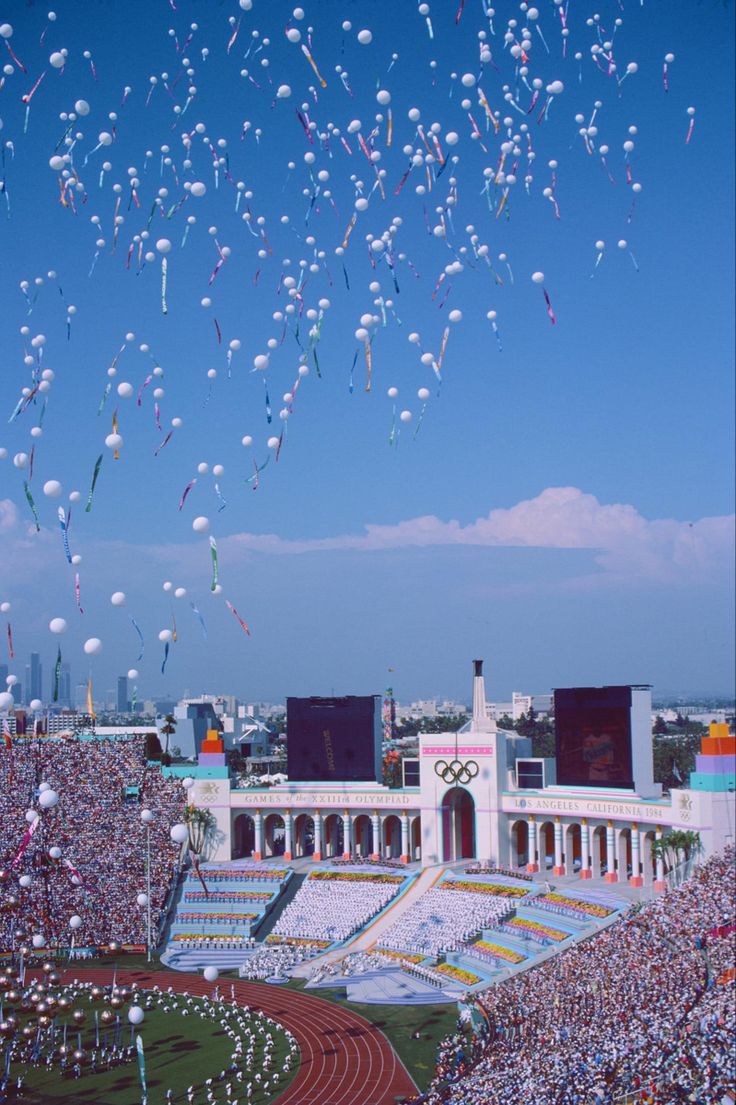 many balloons are flying in the air over a stadium