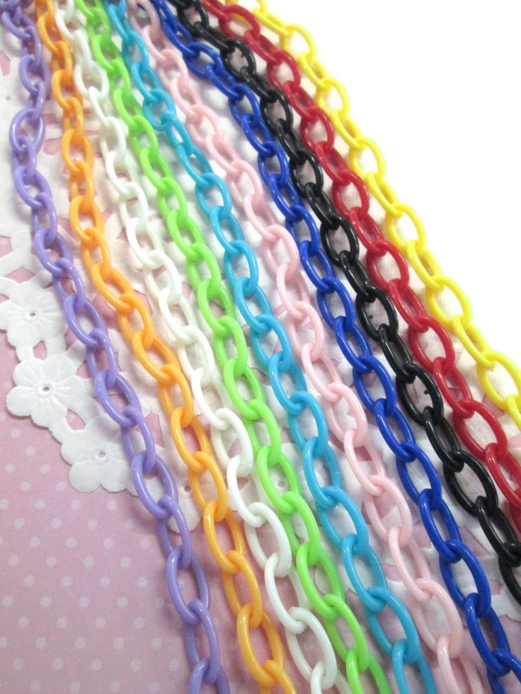 a bunch of different colored chains sitting on top of a pink tablecloth with polka dots