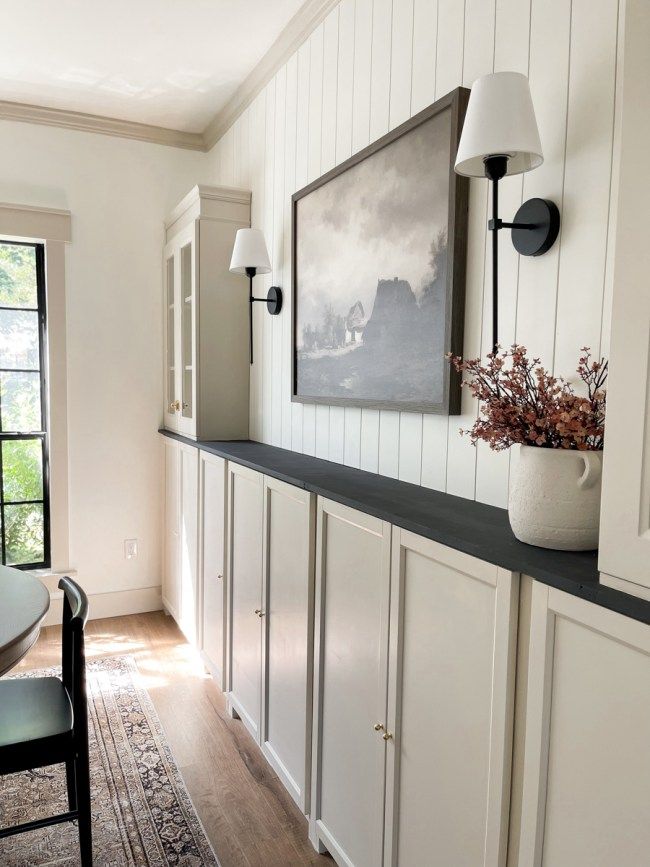 a dining room with white walls and wood flooring on the far wall is a framed painting