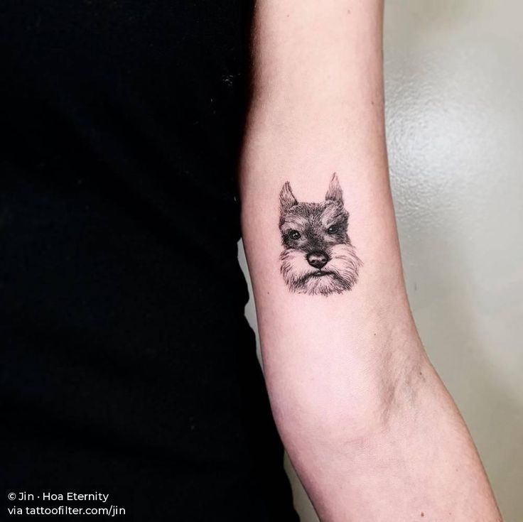 a small black and white dog tattoo on the arm