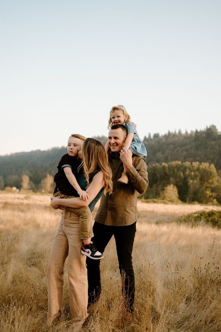 a man and two women are holding a child in the middle of a field