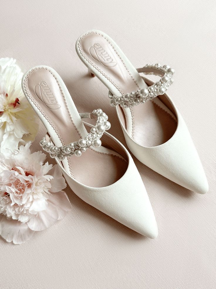 a pair of white shoes sitting on top of a table next to flowers and a bouquet