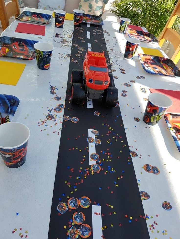 a long table with cars on it and confetti all over the placemats