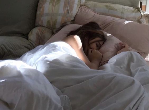 a woman laying in bed with her head on the pillow