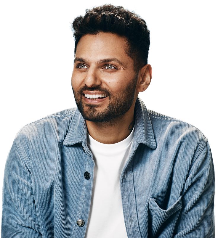 a smiling man in a blue shirt and white t - shirt