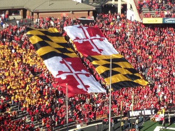 a football stadium filled with people and two large flags flying in the air next to each other