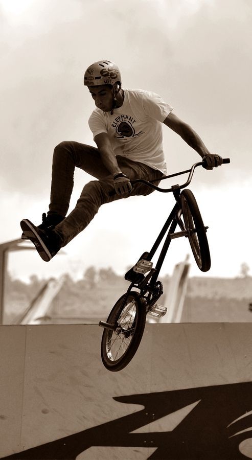 a man riding a bike up the side of a skateboard ramp at a skate park