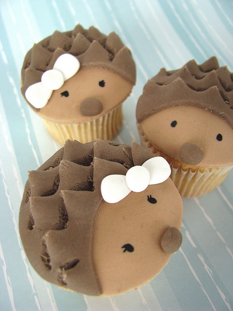 three cupcakes decorated like hedgehogs with bows