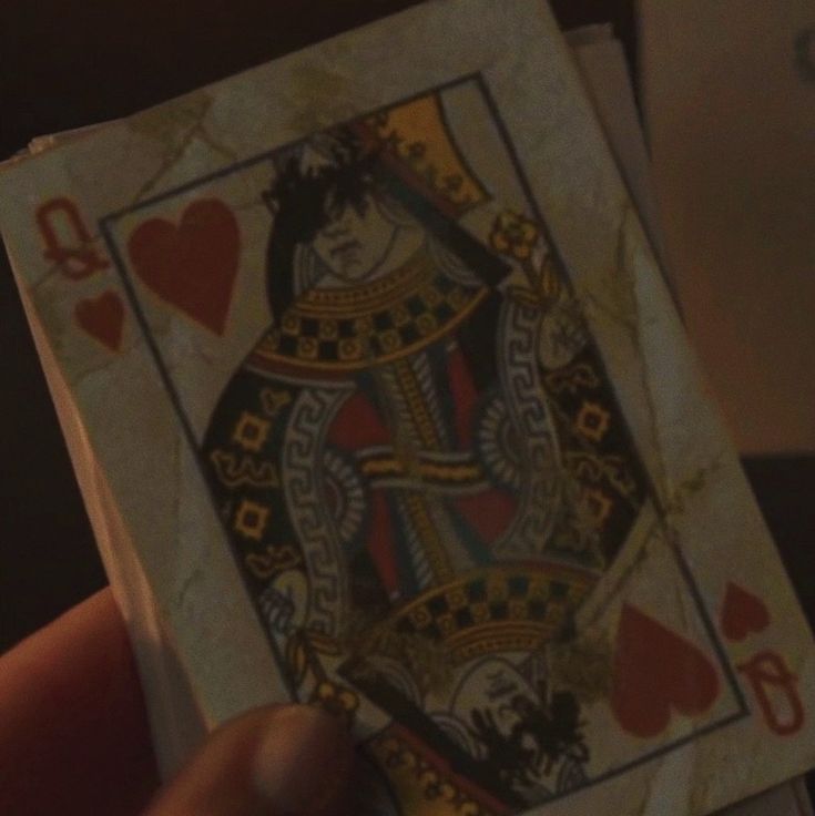 a person holding up a playing card in their hand