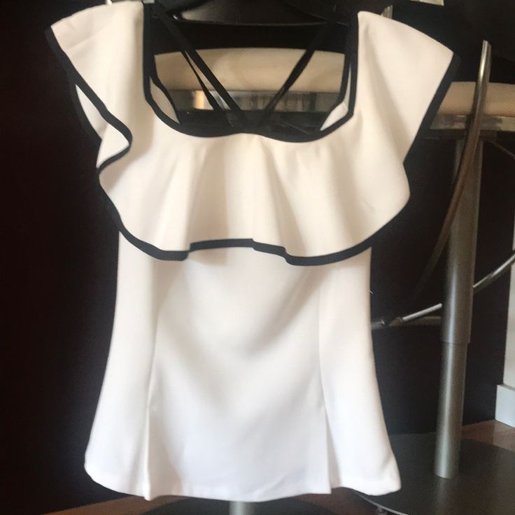 White Off Shoulder Top. Black Trim And Has Ties That Give Halter Look In Front And Tie In Back. Beautiful Fabric With Soft Peplum Shape. Side Zipper. Never Worn. White Short Sleeve Evening Blouse, White Ruffle Top For Night Out, White Ruffled Tops For Night Out, White Ruffled Evening Top, White Short Sleeve Tops For Evening, White Fitted Top Blouse For Party, White Fitted Blouse For Party, Elegant White Stretch Tops, White Fitted Blouse For Night Out