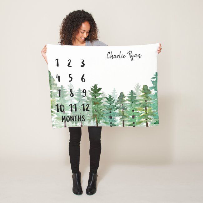 a woman is holding up a large calendar sign with trees on it and the date