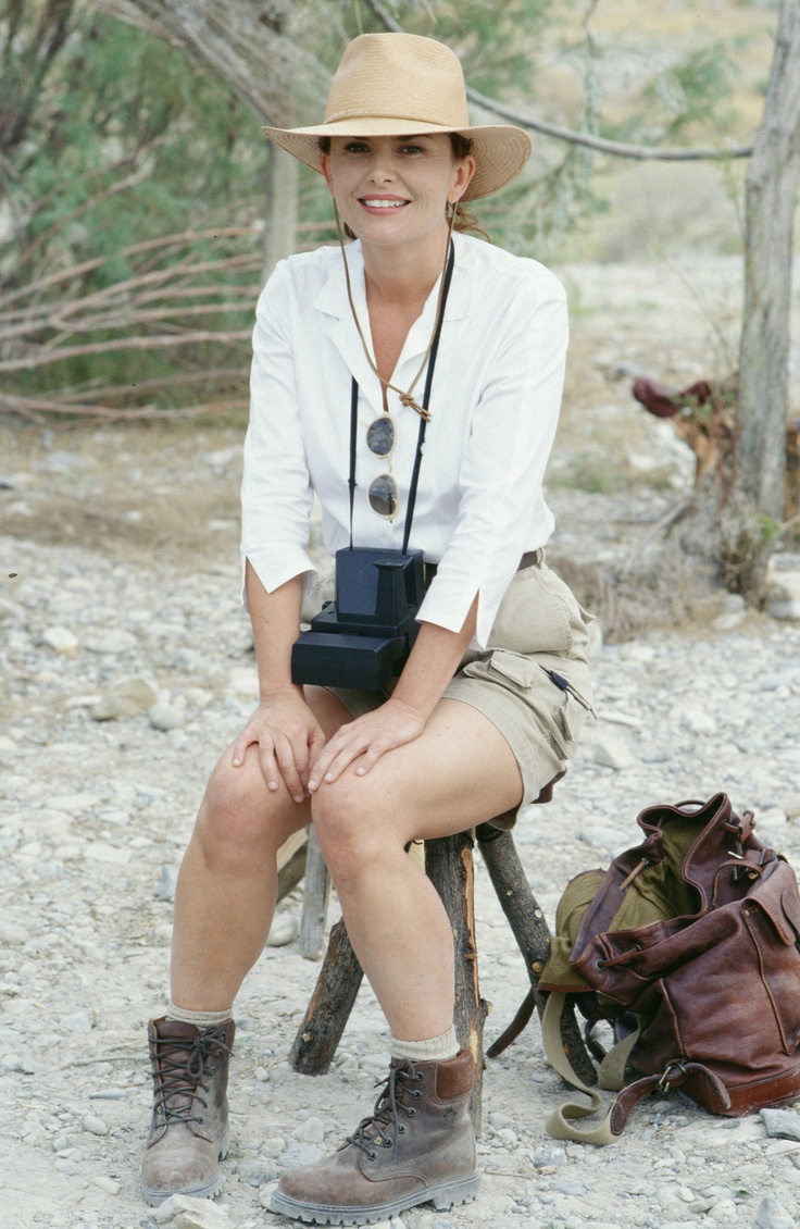 a woman is sitting on a chair with a camera in her hand and a backpack behind her