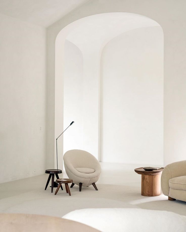 a living room with two chairs and a table in the middle, all white walls