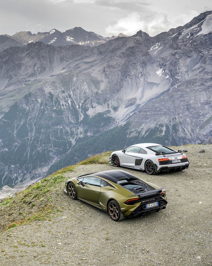 two sports cars parked on top of a mountain