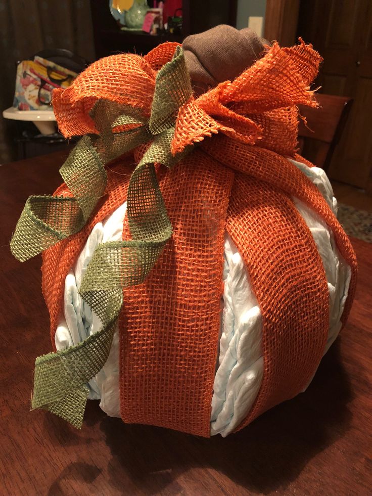 an orange and white pumpkin sitting on top of a wooden table covered in burlocks