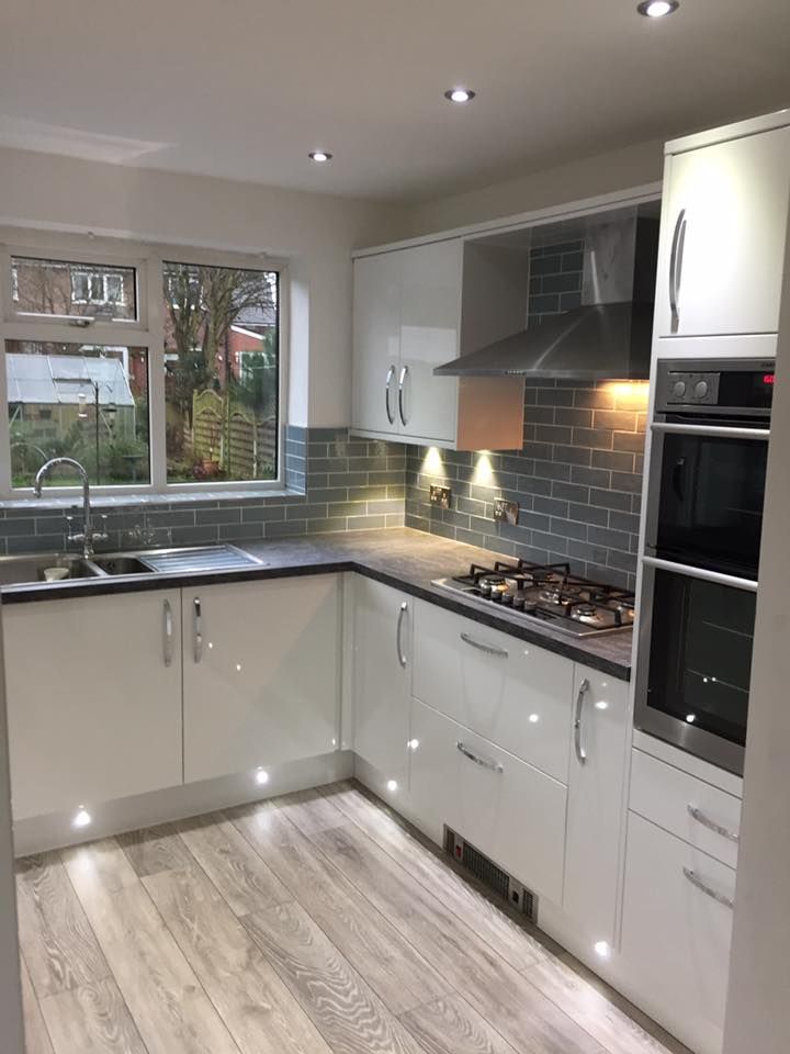 an empty kitchen with white cabinets and wood flooring