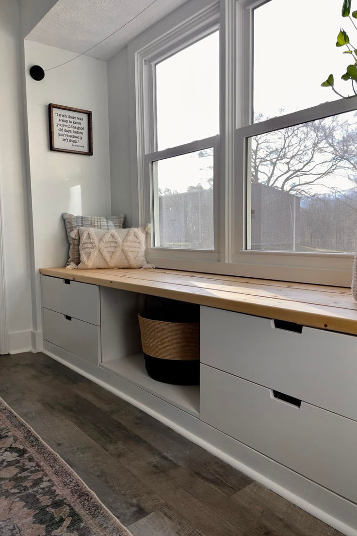 a room with two windows and some storage drawers on the wall next to each other