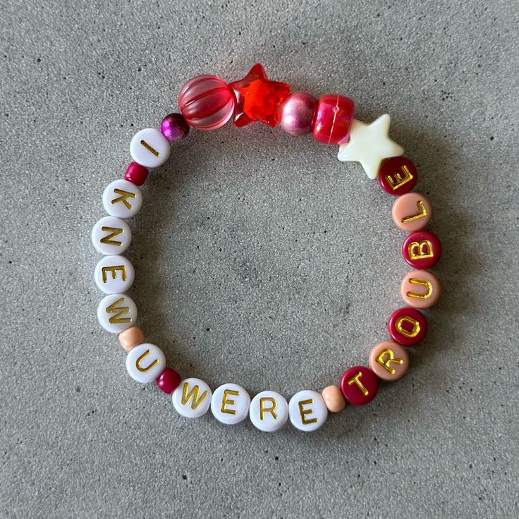 a close up of a beaded bracelet on the ground with words written across it