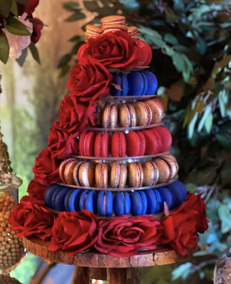 a tower of macaroons with red, white and blue flowers on it in front of a tree