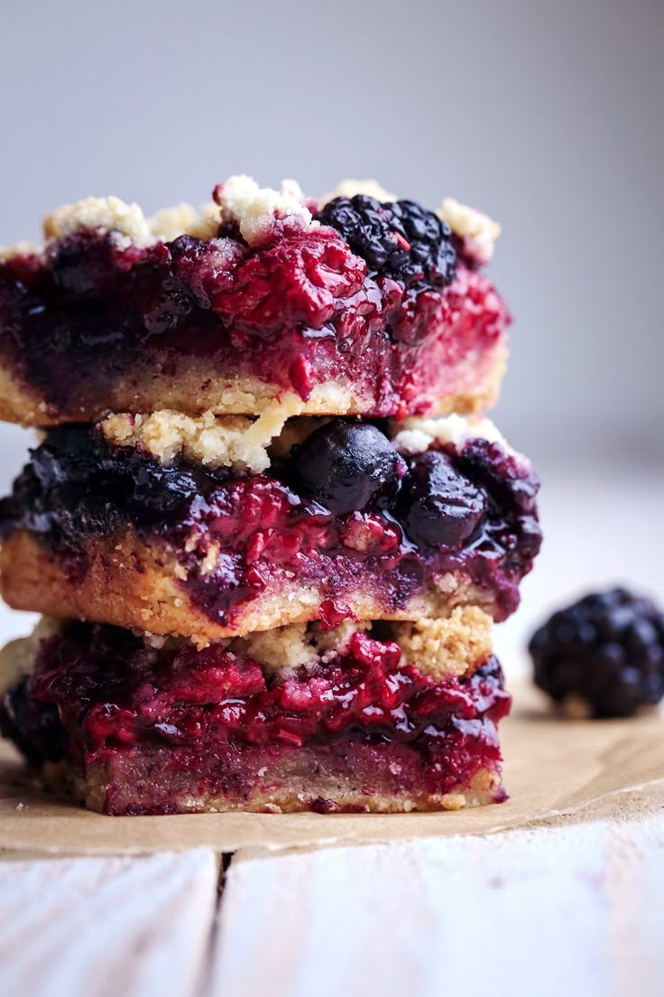 three blueberry bars stacked on top of each other next to blackberries and raspberries