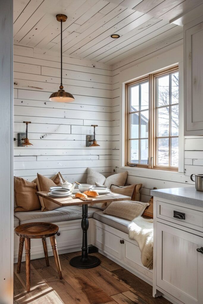 a kitchen with white walls and wood flooring, along with a breakfast nook