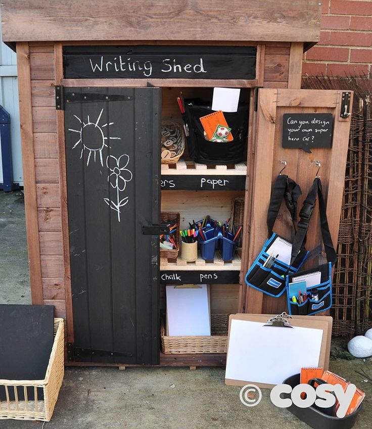 a wooden shed with writing on the door and other items in front of it outside