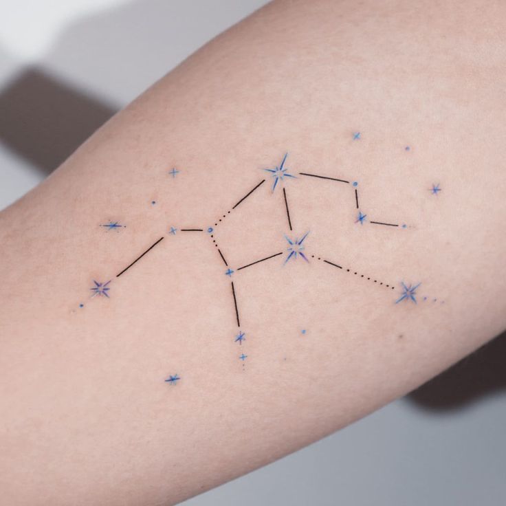 a woman's arm with stars on it and the zodiac sign in blue ink