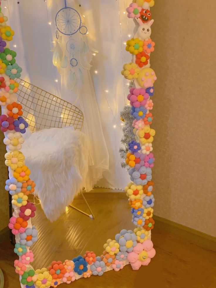 a mirror that has been decorated with flowers and beads on the bottom half of it