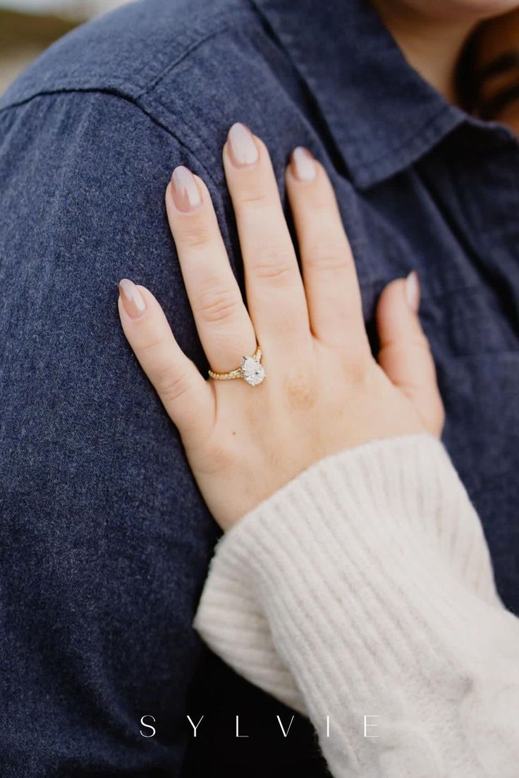 a close up of a person's hand with a engagement ring on their finger