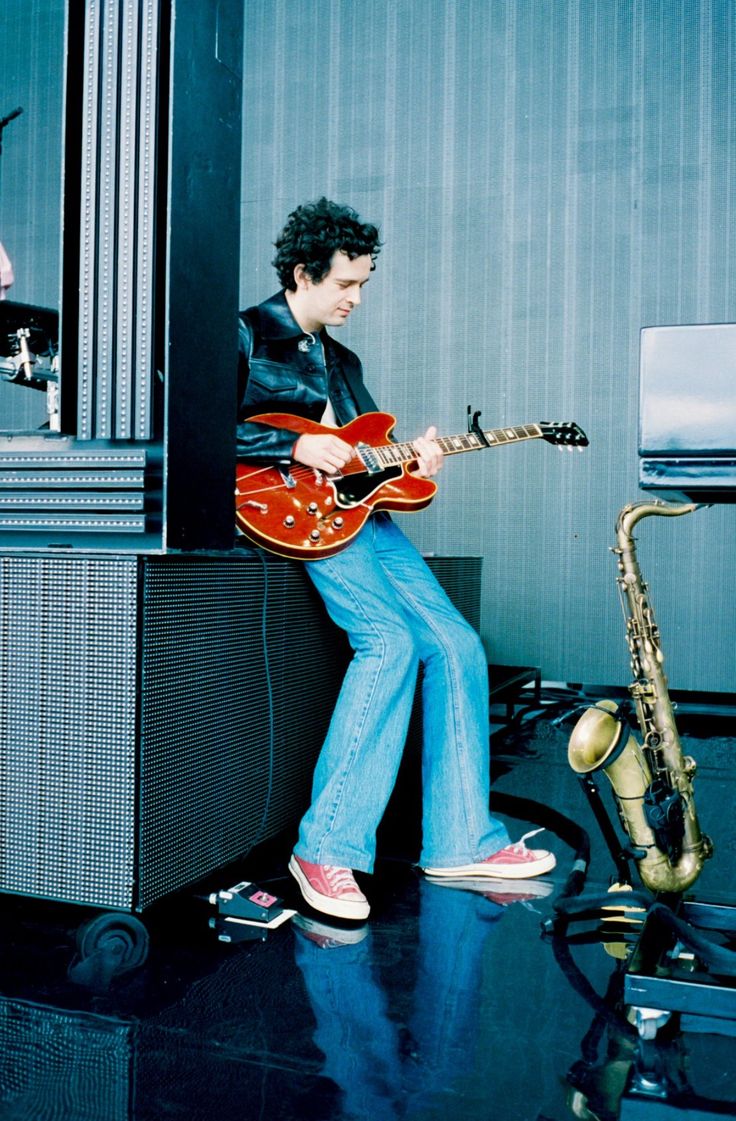 a man sitting on top of a table next to a saxophone and an electric guitar