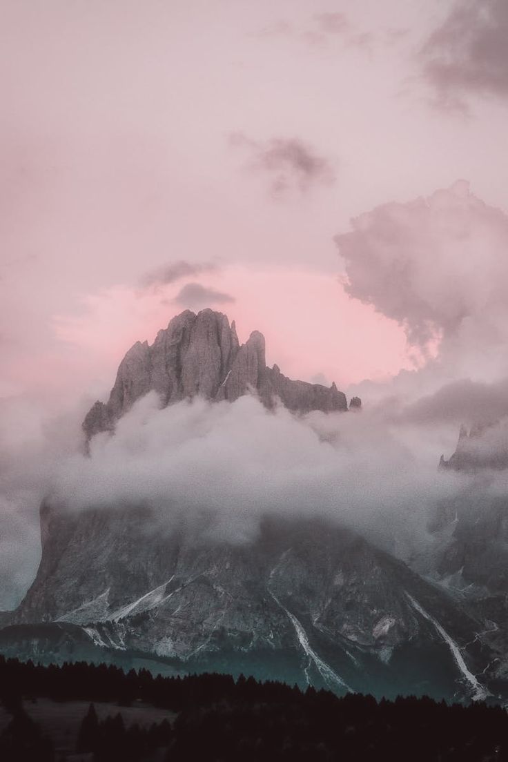 the mountains are covered in clouds and pink hues