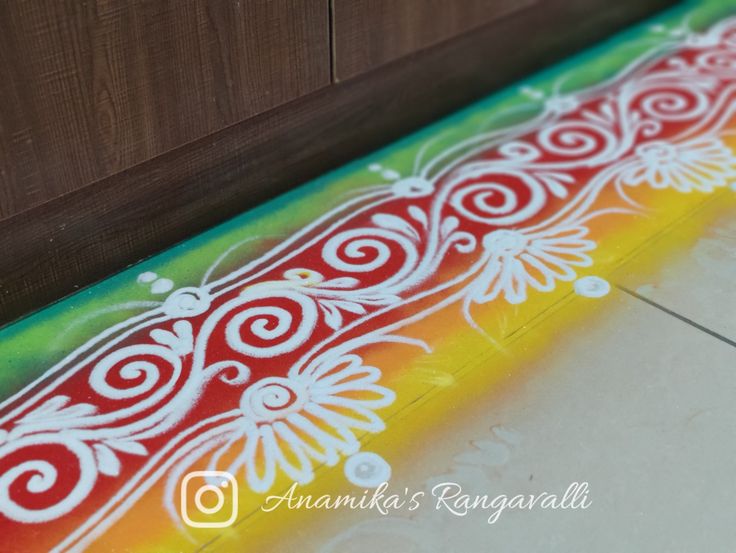 an artistic painting on the floor in front of a wooden door with white and red designs