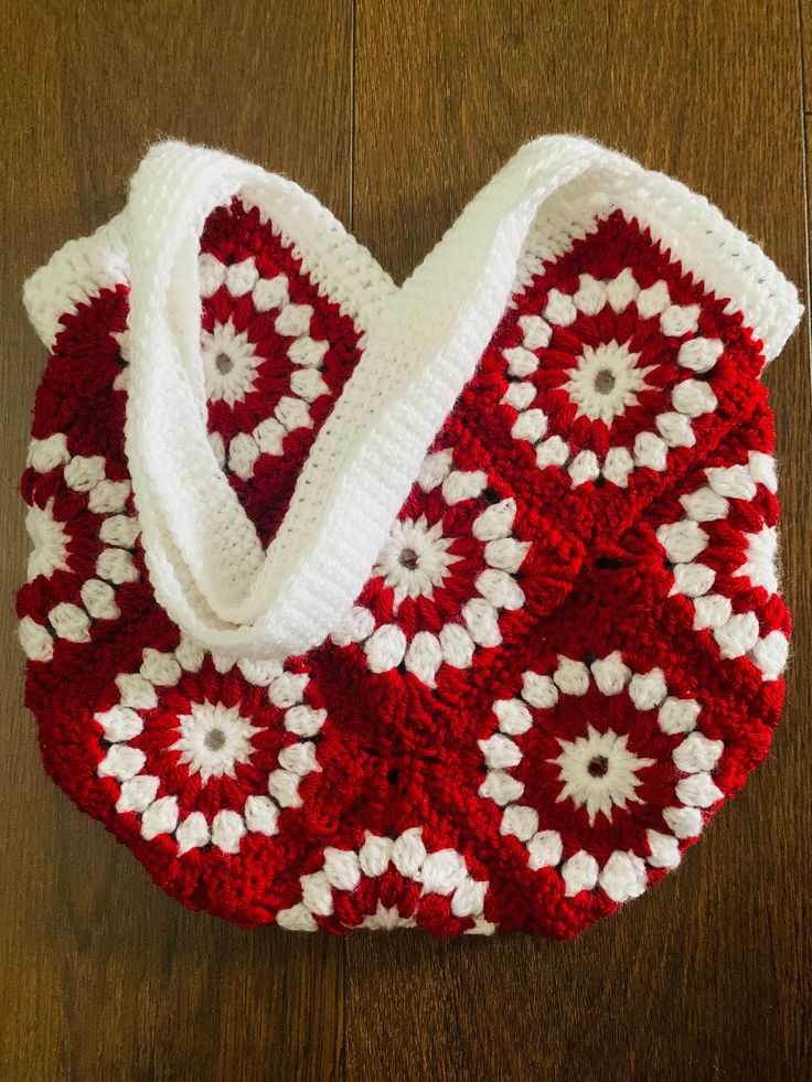 a red and white crocheted bag sitting on top of a wooden floor