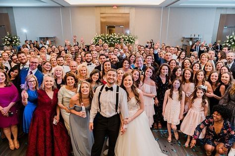 a large group of people posing for a photo in front of an audience at a wedding