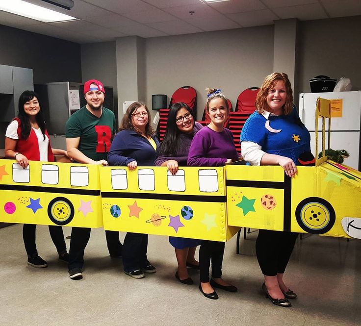 a group of people that are standing in front of a yellow bus shaped like a bus