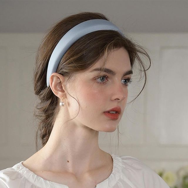 a woman wearing a white shirt and a blue headband is looking off to the side