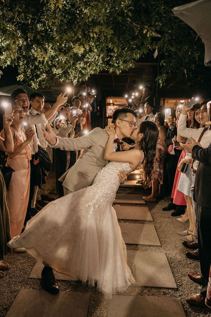 a bride and groom kissing in front of their guests with sparklers on the ground