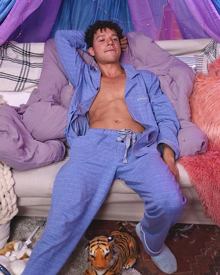 a man laying on top of a bed next to a stuffed animal