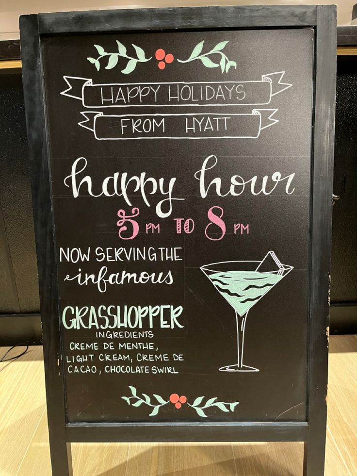 a happy hour chalkboard sign with cocktails on it's front and side