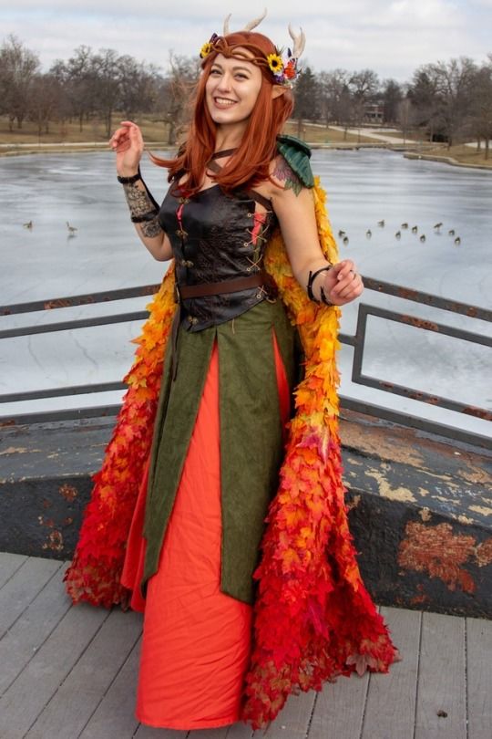 a woman in a costume standing on a dock with her arms out and smiling at the camera