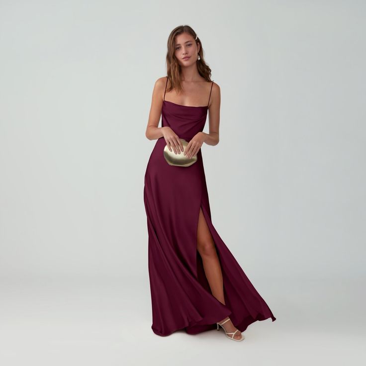 a woman in a long maroon dress holding a gold clutch and posing for the camera