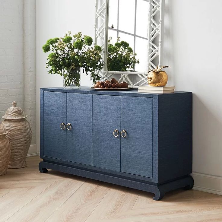 a blue cabinet sitting in front of a mirror next to a vase filled with flowers