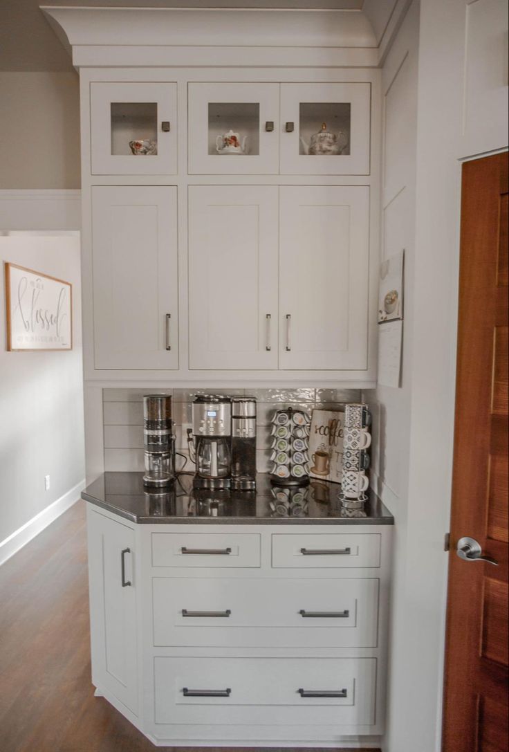 a kitchen with white cabinets and black counter tops