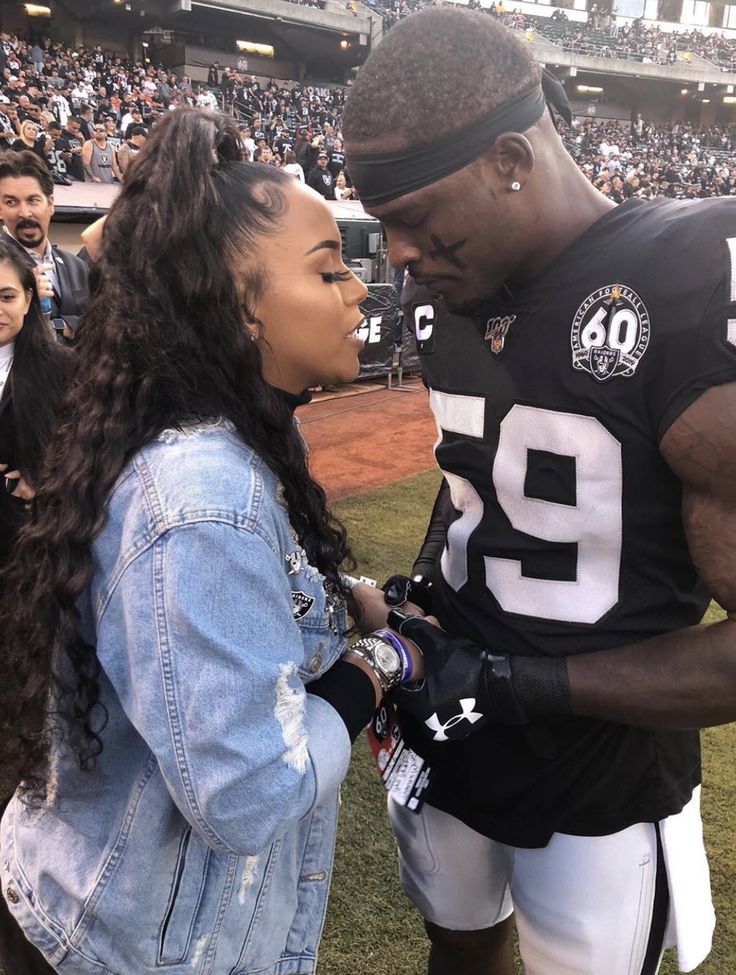 a man and woman standing next to each other at a football game