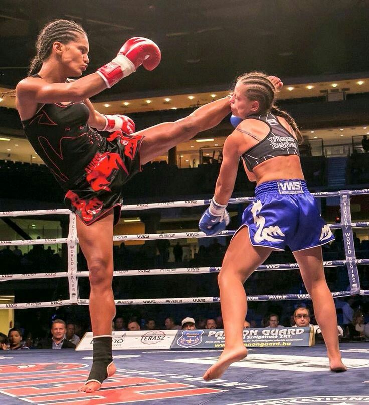 two women kick punches at each other in a boxing ring